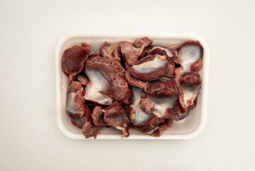 Raw chicken offal in a polystyrene tray on a white background