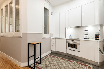 Fototapeta na wymiar Apartment with wooden and hydraulic floors in the kitchen with white furniture and appliances