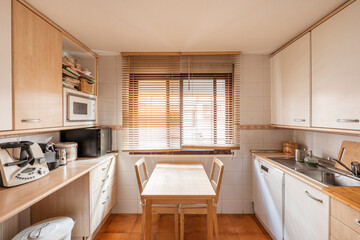 open kitchen with wooden cabinets, windows with wooden shutters and table with matching chairs