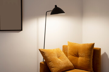 Reading corner in a bedroom with a chaise longue with camel velvet cushions and a black design lamp