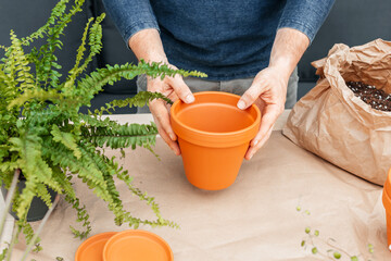 A man holds a terracotta clay pot in his hands. Transplanting houseplants and landscaping at home.