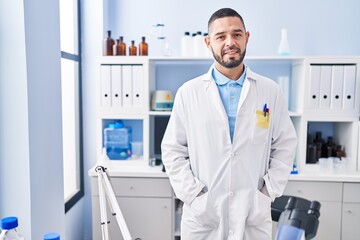 Young latin man scientist smiling confident standing at laboratory
