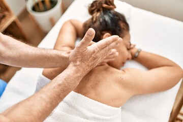 Fototapeta na wymiar Middle age man and woman wearing therapist uniform having back massage session at beauty center