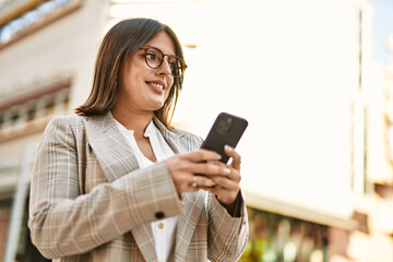 Young hispanic businesswoman smiling happy using smartphone at the city.