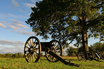 Fototapeta na wymiar A cannon overlooking field with shadows cast on the ground