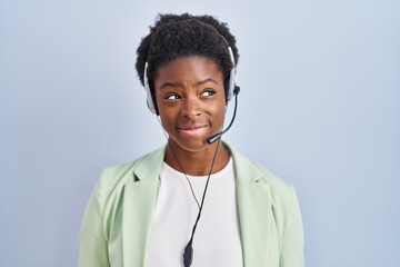 African american woman wearing call center agent headset smiling looking to the side and staring...