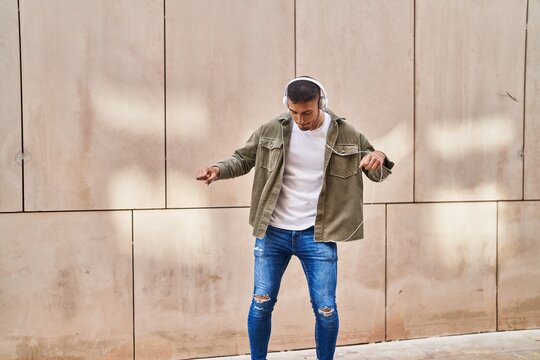 Young hispanic man smiling confident listening to music and dancing at street