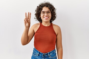 Young hispanic woman wearing glasses standing over isolated background showing and pointing up with fingers number three while smiling confident and happy.