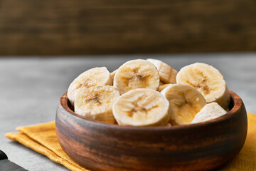 Photo of banana slices in a bowl on a concrete surface