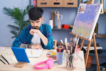 Young hispanic man artist using touchpad drawing at art studio