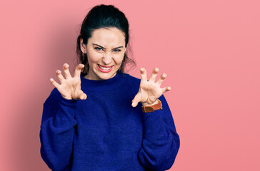 Young hispanic woman wearing casual clothes smiling funny doing claw gesture as cat, aggressive and...