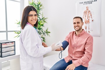 Obraz premium Man and woman doctor and patient having medical consultation using tensiometer at clinic