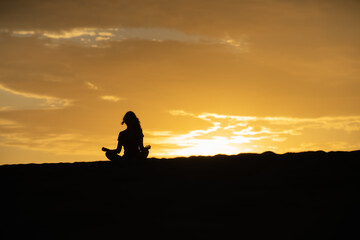 Mujer meditando a contraluz de atardecer amanecer 