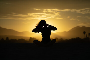 Mujer sentada en atardecer con fonde de montañas 