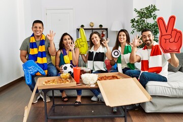 Group of young people wearing team scarf cheering football game doing ok sign with fingers, smiling friendly gesturing excellent symbol