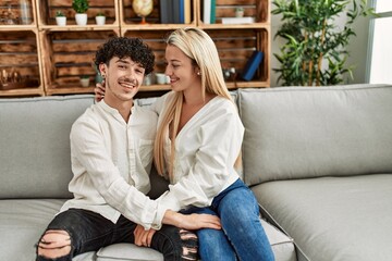 Young couple sitting on the sofa hugging at home.