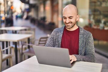 Young man using laptop sitting on table at coffee shop terrace