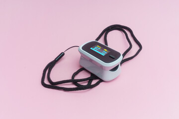 Oximetro y pulsometro sobre fondo rosa.
