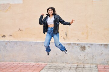 Obraz na płótnie Canvas Young beautiful hispanic woman smiling confident jumping at street