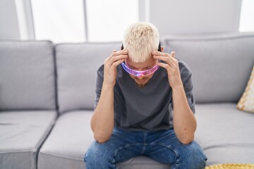 Young caucasian man wearing virtual reality glasses suffering from headache desperate and stressed because pain and migraine. hands on head.