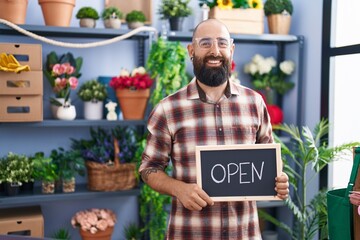 Young hispanic man with beard and tattoos working at florist holding open sign smiling with a happy and cool smile on face. showing teeth. - obrazy, fototapety, plakaty
