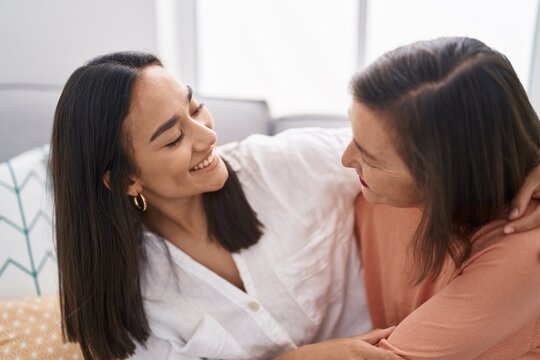 Two women mother and daughter sitting on sofa together at home