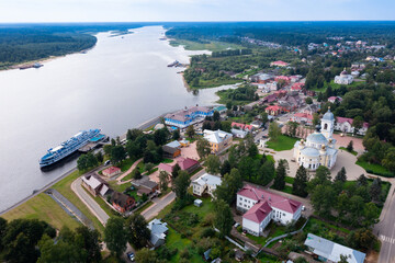 Panoramic aerial view of small Russian town of Myshkin in Yaroslavl Oblast on bank of Volga river on sunny summer day overlooking residential buildings, churches and river station