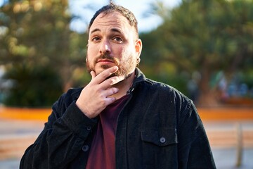Young hispanic man standing with doubt expression at park