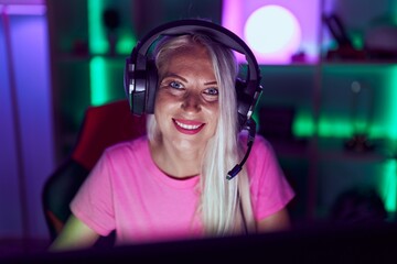 Young blonde woman streamer smiling confident using computer at gaming room