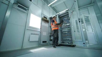 Electrical engineer working check the electric current voltage and overload at front of load center cabinet or consumer unit for maintenance in main power distribution system room.