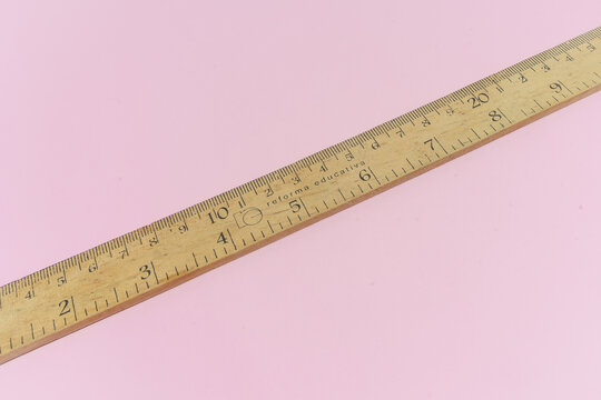 Regla de madera sobre fondo rosa.