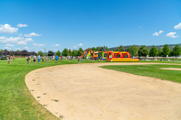 Families play at Pavilion Park during a summer festival and fair in the Spokane Washington suburb of Liberty Lake, Washington. - obrazy, fototapety, plakaty