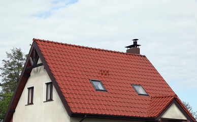 Modern house with red roof against cloudy sky