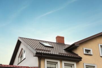Beautiful house with brown roof against blue sky, low angle view