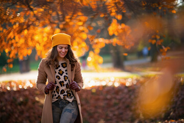 happy trendy woman in brown coat and yellow hat