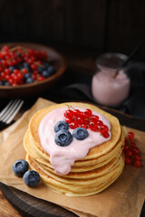Tasty pancakes with natural yogurt, blueberries and red currants on table