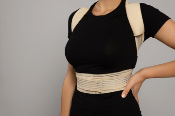 Closeup view of woman with orthopedic corset on grey background. Space for text