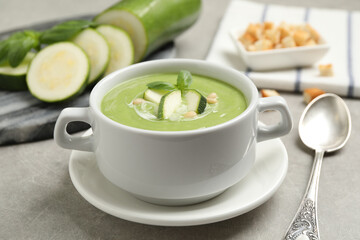 Tasty homemade zucchini cream soup served on grey table