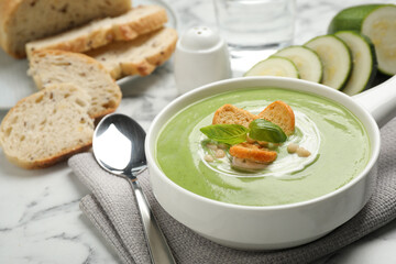 Tasty homemade zucchini cream soup served on marble table
