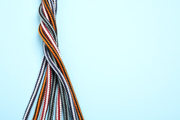 Top view of twisted colorful ropes on light blue background, space for text. Unity concept