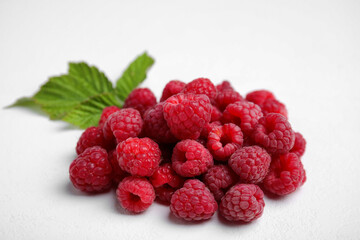 Fresh red ripe raspberries with green leaves on white background