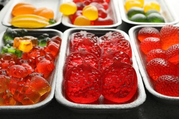 Different delicious gummy candies on grey table, closeup