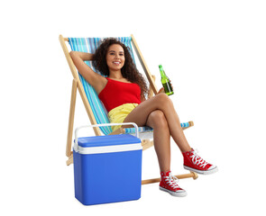 Happy young African American woman with bottle of beer resting in deck chair near cool box on white...