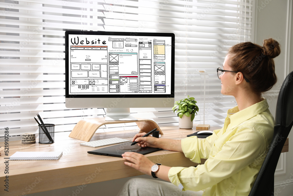 Wall mural designer creating website on computer at wooden table