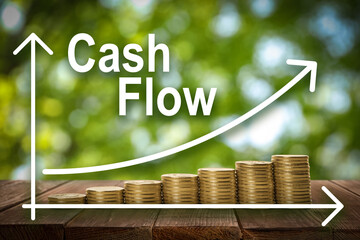 Cash Flow concept. Illustration of increase graph and stacked coins on wooden table against blurred...