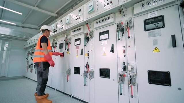 Electrical engineer working check the electric current voltage and overload at front of load center cabinet or consumer unit for maintenance in main power distribution system room.