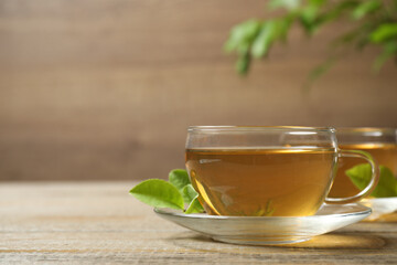 Cups of green tea and leaves on wooden table. Space for text