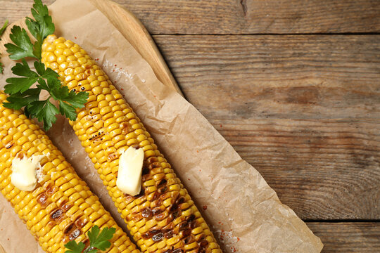 Tasty grilled corn on wooden table, top view