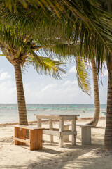 Mesa y bancos bajo las palmeras en el mar caribe de Mahahual. Camping de mahahual 