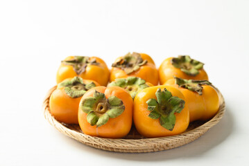 Ripe persimmon fruit in basket on white background